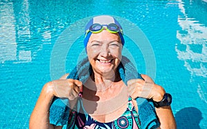 An elderly woman who enjoys the swimming pool. One people with large smile. Blue swimming cap and goggles. Healthy lifestyle by