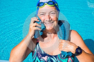 An elderly woman who enjoys the swimming pool. One people with large smile. Blue swimming cap and goggles. Healthy lifestyle by