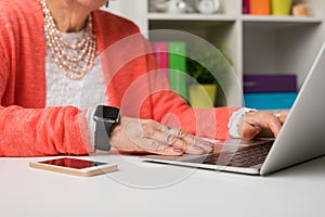 Elderly woman working at the office with laptop computer