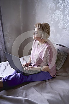 elderly woman works with laptop at home