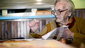 Elderly woman writing on a piece of paper at home. Retired people hobbies