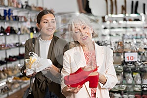 Elderly woman and young woman choosing mules and sneakers