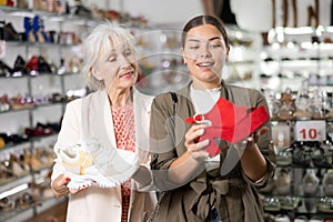 Elderly woman and young woman choosing mules and sneakers