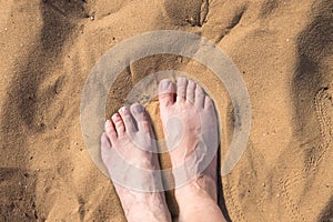 elderly womans feet at the hot sand, top view