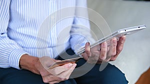 Elderly womans hands closeup using tablet holding credit card buy on internet. Make payments, enjoy easy instant money