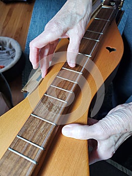 Elderly womans hands play Appalachian dulcimer