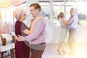 Elderly woman is dancing slow unhurried dance in hugs arms of her male partner. photo