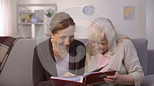 Elderly women looking through old photos in family album, pleasure memories