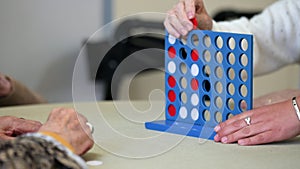 Elderly women playing a traditional strategy game to form 4 chips row at nursing home.