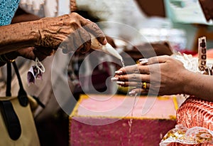 Elderly women pour the conch into their wedding hands. Asian wedding ceremony creating a shared future for men and women. Marriage