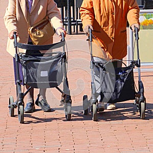 Two elderly women street rollator walking outdoor