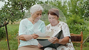 Elderly women view photos in an album outdoors