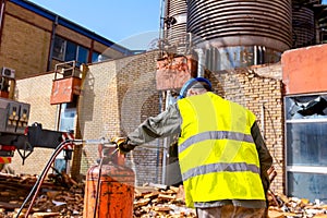 Elderly worker is replacing gas cylinders for gas welding equipment to cutting scrap metal with torch at junkyard