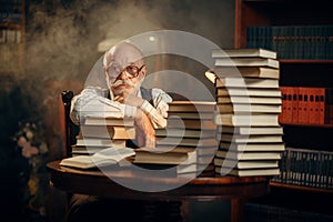 Elderly writer sitting at the table with books