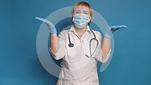 Eldery caucasian doctor lady in white coat on blue background. She wear stethoscope and make frustrated gestures