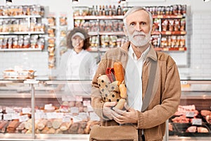 Eldery man holding bag with sausages. photo