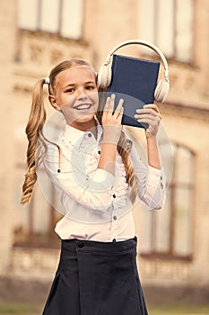 Elearning and modern methods. Girl cute schoolgirl hold book and headphones. Knowledge assimilate better this way. Audio
