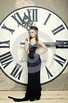 Elecant Queen in black dress posing near clock