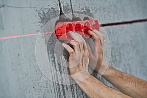 Elecrician work. Installing wall electric outlet with laser level
