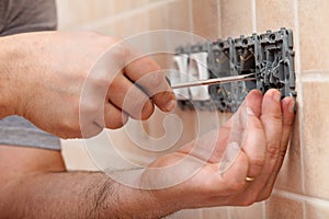 Electician hands installing electrical wall fixture