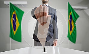 Election or referendum in Brazil. Voter holds envelope in hand above ballot. Brazilian flags in background