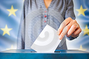 elections in European Union. The hand of woman putting her vote in the ballot box. EU flag in the background