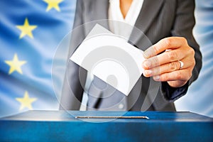 elections in European Union. The hand of woman putting her vote in the ballot box. EU flag in the background