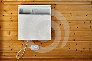 Electric air heater on a wooden wall connected to the mains indoors