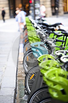 Electric bicycles with baskets for public rent stand on street in Paris waiting for cyclists