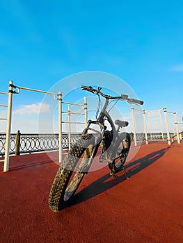 An electric bike on the sports field. Black fat bike with thick wheels. Concept of a healthy lifestyle
