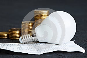 Electric bill. Energy saving. Energy saving lamp. Money coins on a dark background. Energy saving. Stack of coins