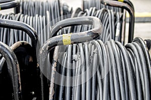 Electric black cables are twisted and stacked in a coil. Cords and wires, electrical and audio equipment, selective focus, tinting
