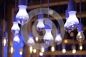 Electric blue light bulbs hang from ceiling, illuminating event