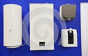 Electric boilers, water heaters display of different sizes and forms, hung on a wall in a shop for sale