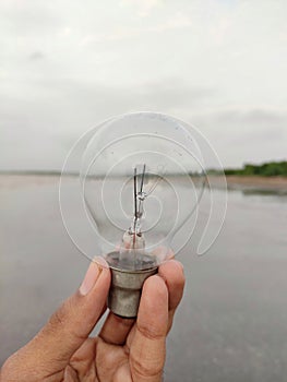 Electric bulb on hand, hand holding bulb with background blur