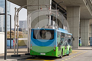 Electric bus at a stop is charged by pantograph. Clean mobility