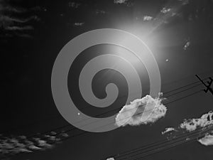 Electric cable in black Sky and white clouds, the sun look at wires on a pole on sunny day