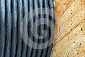 An electric cable in a polymer winding on a wooden coil. A high-voltage cable located on a construction site. Close-up of the