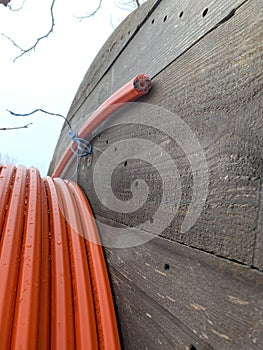 An electric cable of red-orange color in a section against the background of a wooden reel close-up