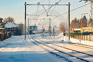 Electric cables on snow covered train tracks between houses and buildings