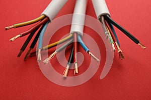 Electric cables with wires on red background, closeup view