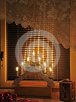 Electric candles on window with Christmas decoration.