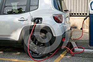 Electric car being recharged, connected with the red cable to the electrical control unit