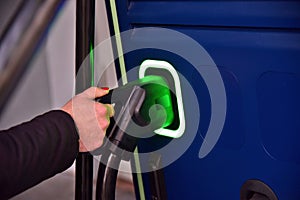 Electric car charger connector is held by a woman in the charger