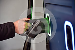 Electric car charger connector woman holds in charger