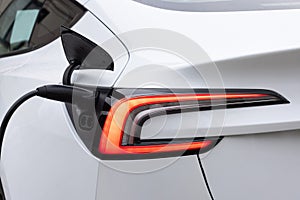 Electric car charging. Electric vehicle charging port plugging in car. Charging technology, Clean energy filling