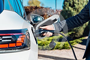 Electric car charging. Man`s hand inserting the electrical connector to the electric car.