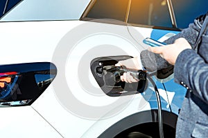 Electric car charging. Man`s hand inserting the electrical connector to the electric car.