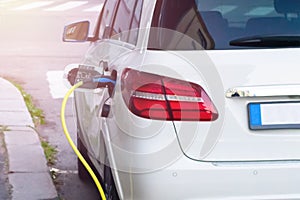 Electric car is charging on parking lot on electric car charging station in the street.