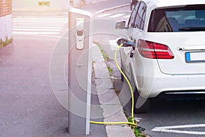 Electric car is charging on parking lot on electric car charging station in the street. Green alternative energy